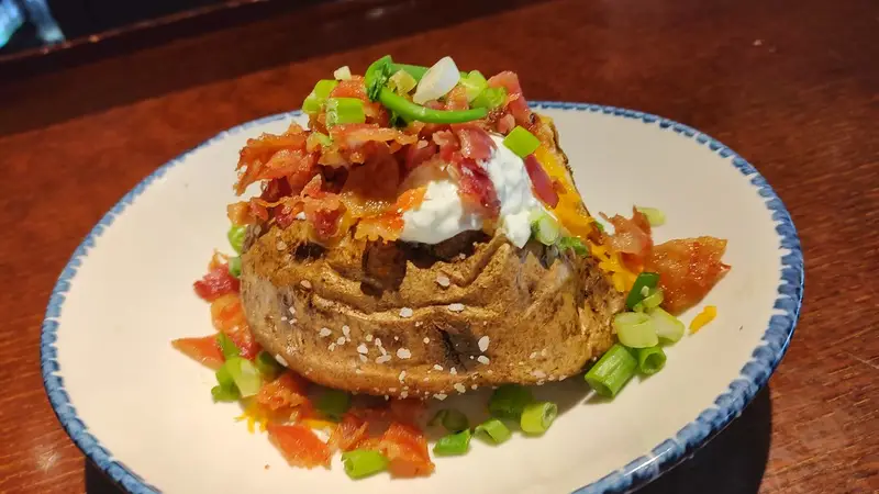 Loaded baked potato topped with sour cream, shredded cheese, bacon bits, and chopped green onions