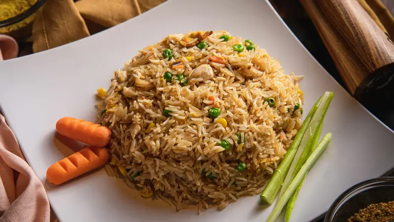 Seasoned rice pilaf with peas and carrots mounded on a white plate – LongHorn Rice Pilaf side