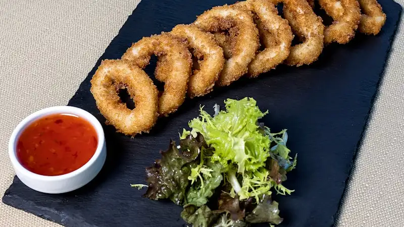 Basket of crispy fried Texas Tonion onion petals with dipping sauce